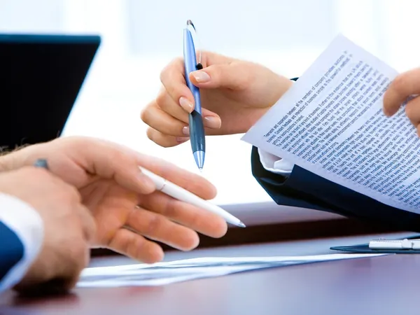Deux mains et un stylo sur un document, lors d'un rendez-vous de conseil