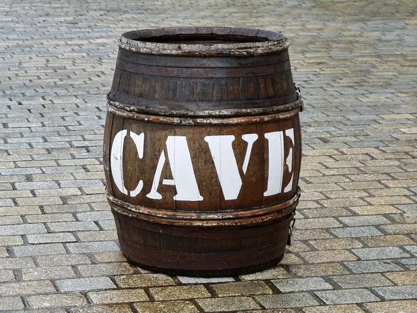 Un tonneau marqué CAVE posé sur les pavés devant un caviste