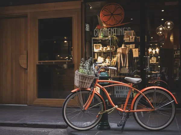 Un vélo orange garé devant la vitrine d'une boutique de décoration