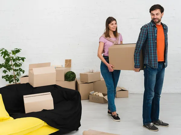 Un couple porte des cartons de déménagement, Déménagements.