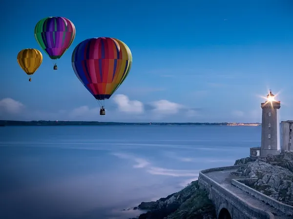 Des montgolfières au-dessus d'un phare, au bord de la mer